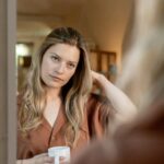 bewijsdrang, vrouw kijkt naar zichzelf in de spiegel