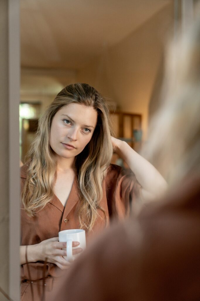 bewijsdrang, vrouw kijkt naar zichzelf in de spiegel